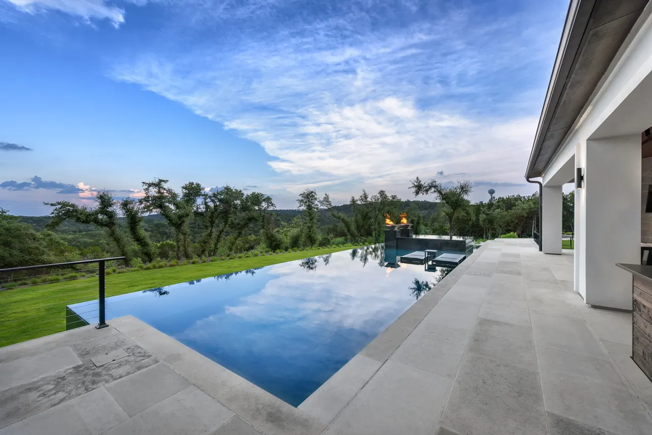 Infinity-edge estate pool running the width of a West Lake Hills terrace under a wide Hill Country sky — Estate Infinity by GB IV Designs