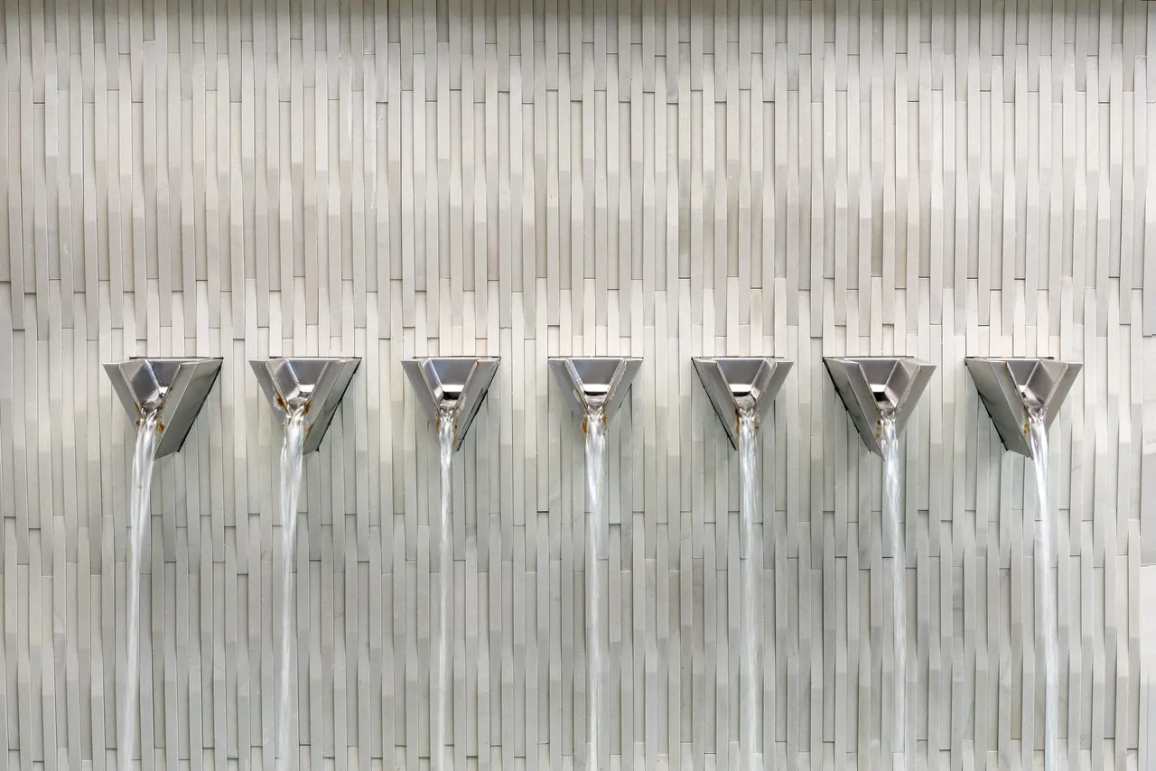 Fluted concrete water walls with scuppers by GB IV Designs, Bee Cave