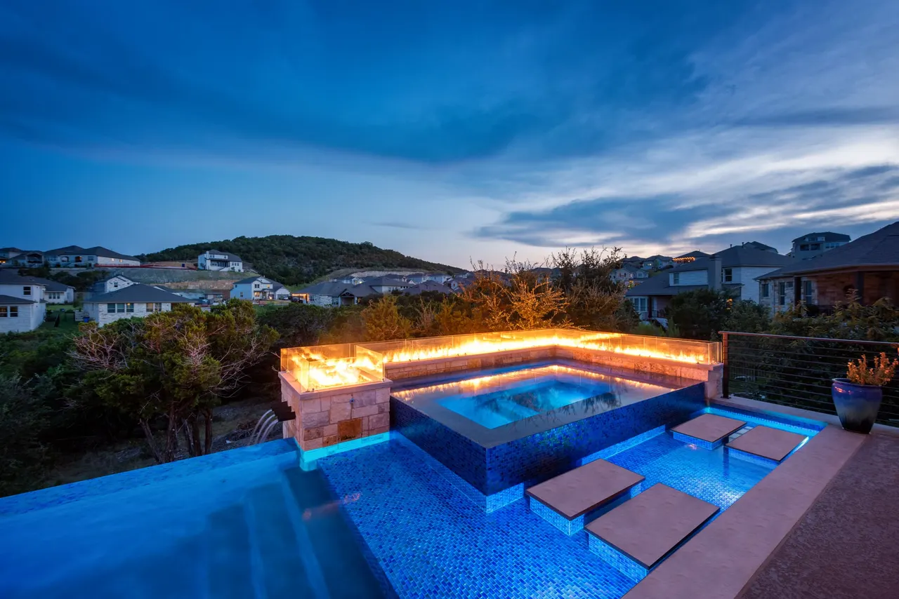 Terraced modern pool with linear fire feature at dusk by GB IV Designs, Westlake